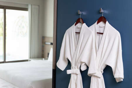 Clean white bathrobes hanging on wall