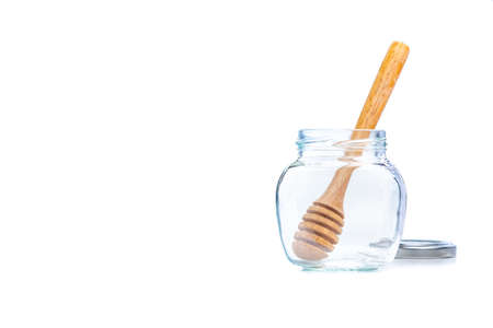 Wooden honey dipper in an empty glass jar on white background and copy spaceの写真素材