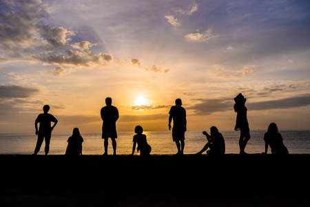Silhouette of people relaxing watching colorful sunrise at a beach, roof for copy spaceの写真素材