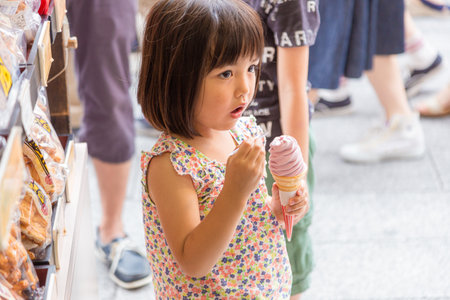 Tokyo, Japan - 13 June 2015 - Young little Asian girl enjoy her soft ice cream outside of a snack shop in Tokyo, Japan on June 13, 2015のeditorial素材