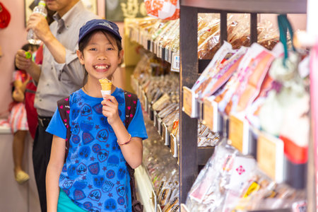 Tokyo, Japan - 13 June 2015 - Young little Asian girl enjoy her soft ice cream outside of a snack shop in Tokyo, Japan on June 13, 2015のeditorial素材