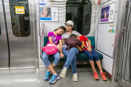 Tokyo, Japan - 14 June 2015 - Tired Asian mom and two daughters sit in Japanese subway train in Tokyo, Japan on June 14, 2015のeditorial素材