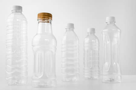 Plastic bottles in various shapes and sizes on white table and background, monotone, health and environment conceptの写真素材