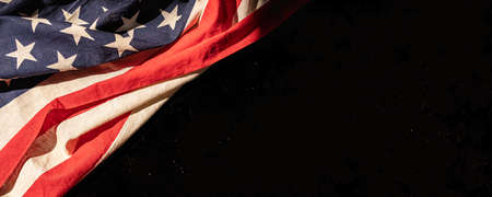 Top view or flatlay of wrinkled United State of America, USA, flag on rough black background with...