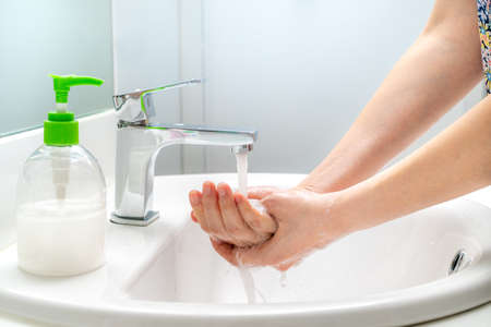 Woman washing her hands with soap at the sink for good hygiene and to prevent covid-19 virusの写真素材