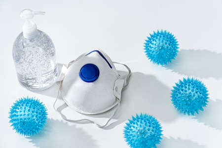 Anti-septic hand gel and N95 mask on white table with rubber spiky COVID-19 virus toy health conceptの写真素材