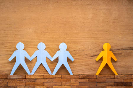 Paper cutout human figures separate by wide space between them on woodenの写真素材