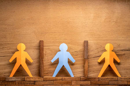Paper cutout human figures separate by wooden blocks on wooden