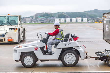 Fukuoka, Japan - 14 July 2019 - Airport baggage handler drives a baggage truck at Fukuoka airport in Japan on July 14, 2019のeditorial素材