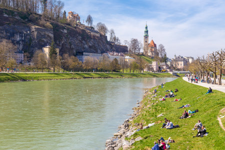 Salzburg, Austria - 9 April 2015 - People hang around along the river bank on a fine spring day in Salzburg, Austria on April 9, 2015のeditorial素材