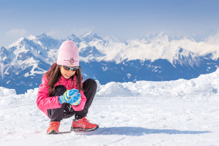 Innsbruck, Austria - 11 April 2015 - Happy young girl make snow ball on Nordkette ski area of Innsbruck, Austriaのeditorial素材