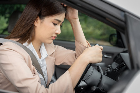 Sad and tired young Asian female office worker sitting in her car thinking of her problems at workの写真素材