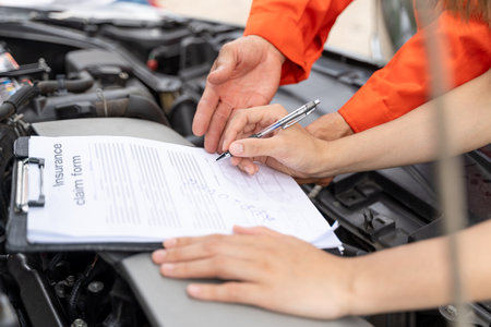 Close up hands of a male car insurance agent showing his female client where to sign on the insurance claim formの写真素材