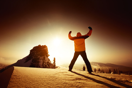 Man stands in winner pose on the top of a mountain. Sheregesh resort, Siberia, Russiaの写真素材