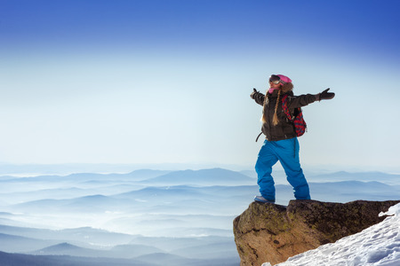Happy snowboarder stands on big rock on mountains backdrop. Sheregesh resort, Siberia, Russiaの写真素材