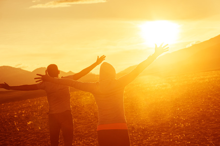 Happy couple stands o sunset with rised hands. Fun sunset conceptの写真素材