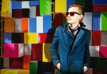 Man in blue cloak stands on color brick wall and posingの写真素材