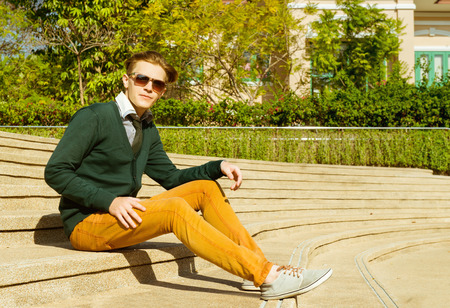 Fashion handsome man sits on stoned stairsの写真素材