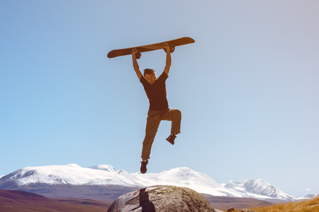Happy snowboarder jumps on the snow mountains backdrop skiingの写真素材