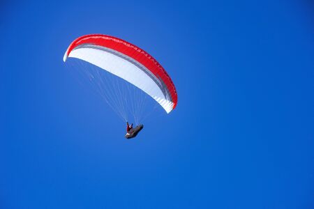 Skydiver flies on the blue sky background