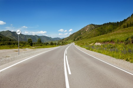 Straight road goes to horizon on background of sky and mountains. Altay mountains, Siberia, Russia.の写真素材