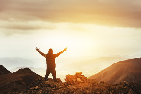 man stands in winner pose on the top of mountain on valleys backdropの写真素材