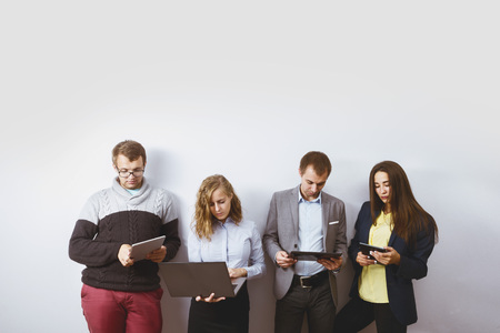 Group of young business men friends stands on white wall with gadgets. Team conceptの写真素材