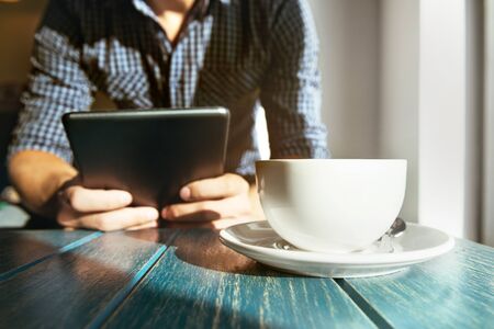 Man with tablet computer works in cafe with cup of coffee. Closeup portrait conceptの写真素材