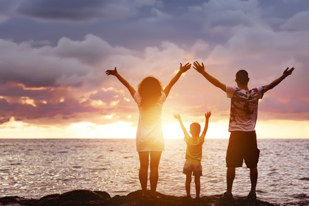 Happy family with son greetings sunset and seaの写真素材