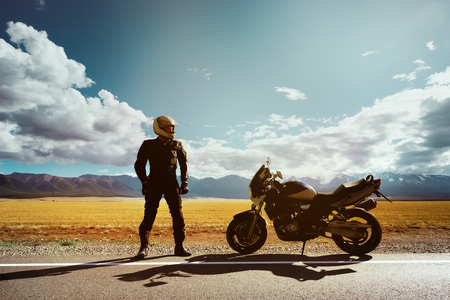 Biker with motorcycle stands on the roadの写真素材