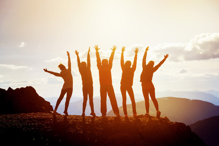 Five happy friends with raised arms