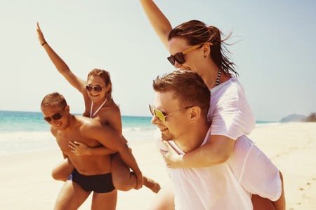 Two couples friends fun beach runの写真素材