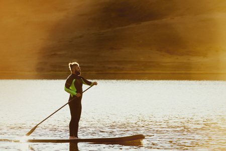 Man swim sup paddle board sunset