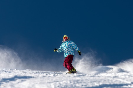 Snowboarder at ski slope against blue sky