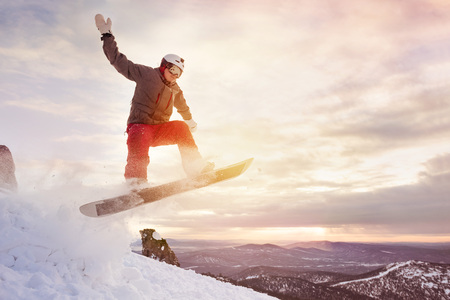 Snowboarder jumps against sunset skyの写真素材