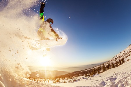 Snowboarder jumps against sunset sunの写真素材