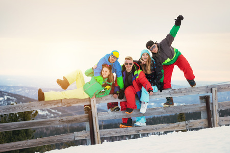 Happy friends skiers and snowboarders sunset mountains