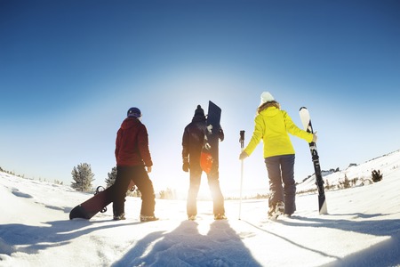 Three friends skiers and snowboarders stands with ski equipment. Ski resort conceptの写真素材