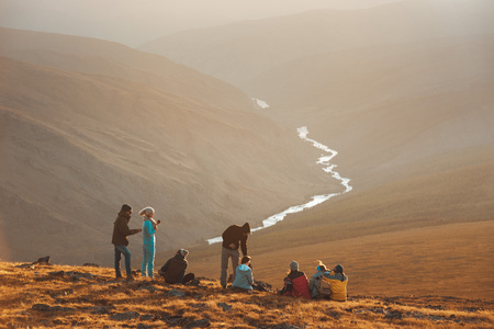 Big group of friends peoples relax on mountain top and looks at sunsetの写真素材
