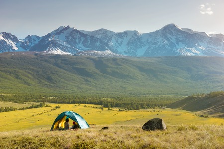 Romantic couple having rest in tent againt mountains at sunset time