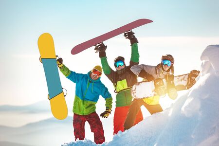 Three happy snowboarders are having fun and posing with snowboardsの写真素材