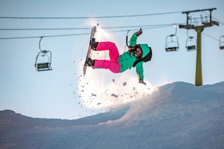 Girl snowboarder jumps from kicker, fails and falls on snowboardの写真素材