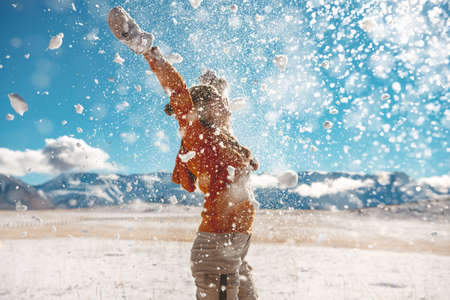 Adult girl throws snow and having fun against mountains. First snow conceptの写真素材