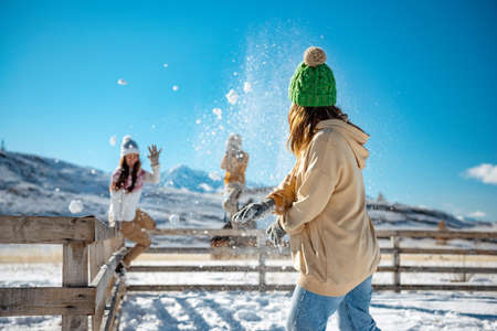 Happy adult girls are having fun and plays in snowballs at first snow in mountains