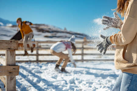 Three girls plays snowballs in mountains. Girl shaking off snow from handsの写真素材