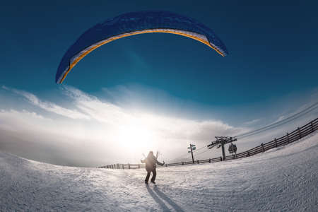 Lonely skydiver is taking off from mountain top at ski resort in sunset time. Sheregesh resort, Siberia, Russiaの写真素材