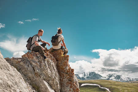 Young hikers relax at big rock or cliff