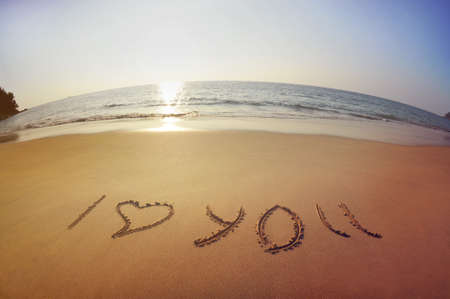 Inscription "I love you" with heart are written on the sand on background of sea and sunset sky. Phuket island, Thailandの写真素材