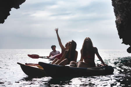 Silhouettes of sporty girls walking on kayaks or canoes at sea lagoon. Kayaking or canoeing conceptの写真素材