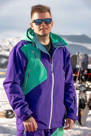 Stylish skiers or snowboarders portrait at ski resort. Young guy in bright ski clothesの写真素材
